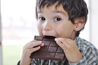 Little cute kid eating hygienic chocolate made at snack and candy facility with perfect compliance from hygiene automation of handwashing and footwear