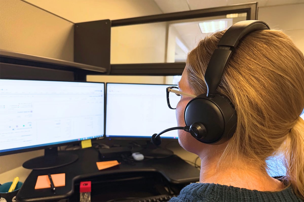 female-wearing-headset-at-workstation-with-two-monitors